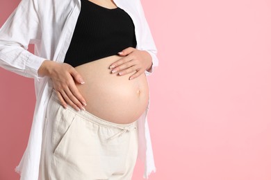 Young pregnant woman on pink background, closeup. Space for text