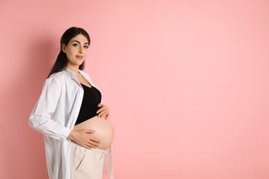 Portrait of beautiful pregnant woman on pink background, space for text