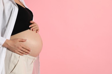 Photo of Young pregnant woman on pink background, closeup. Space for text