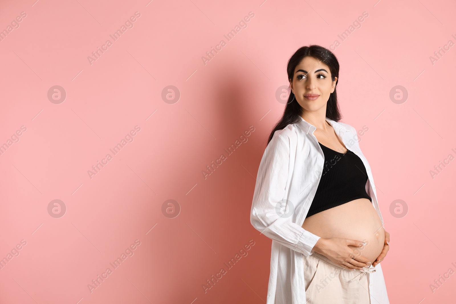 Photo of Portrait of beautiful pregnant woman on pink background, space for text