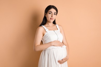 Photo of Portrait of beautiful pregnant woman on beige background