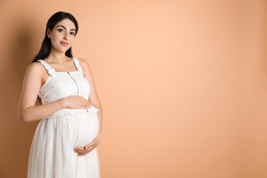 Photo of Portrait of beautiful pregnant woman on beige background, space for text