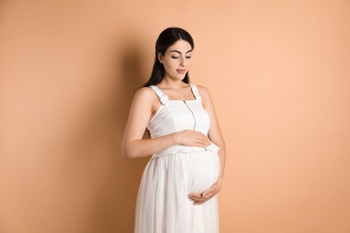 Portrait of beautiful pregnant woman on beige background