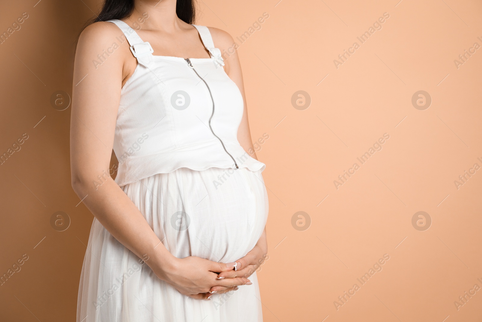 Photo of Young pregnant woman on beige background, closeup. Space for text