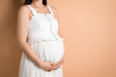 Photo of Young pregnant woman on beige background, closeup. Space for text