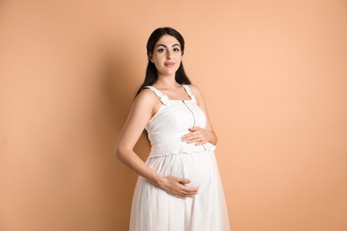 Portrait of beautiful pregnant woman on beige background