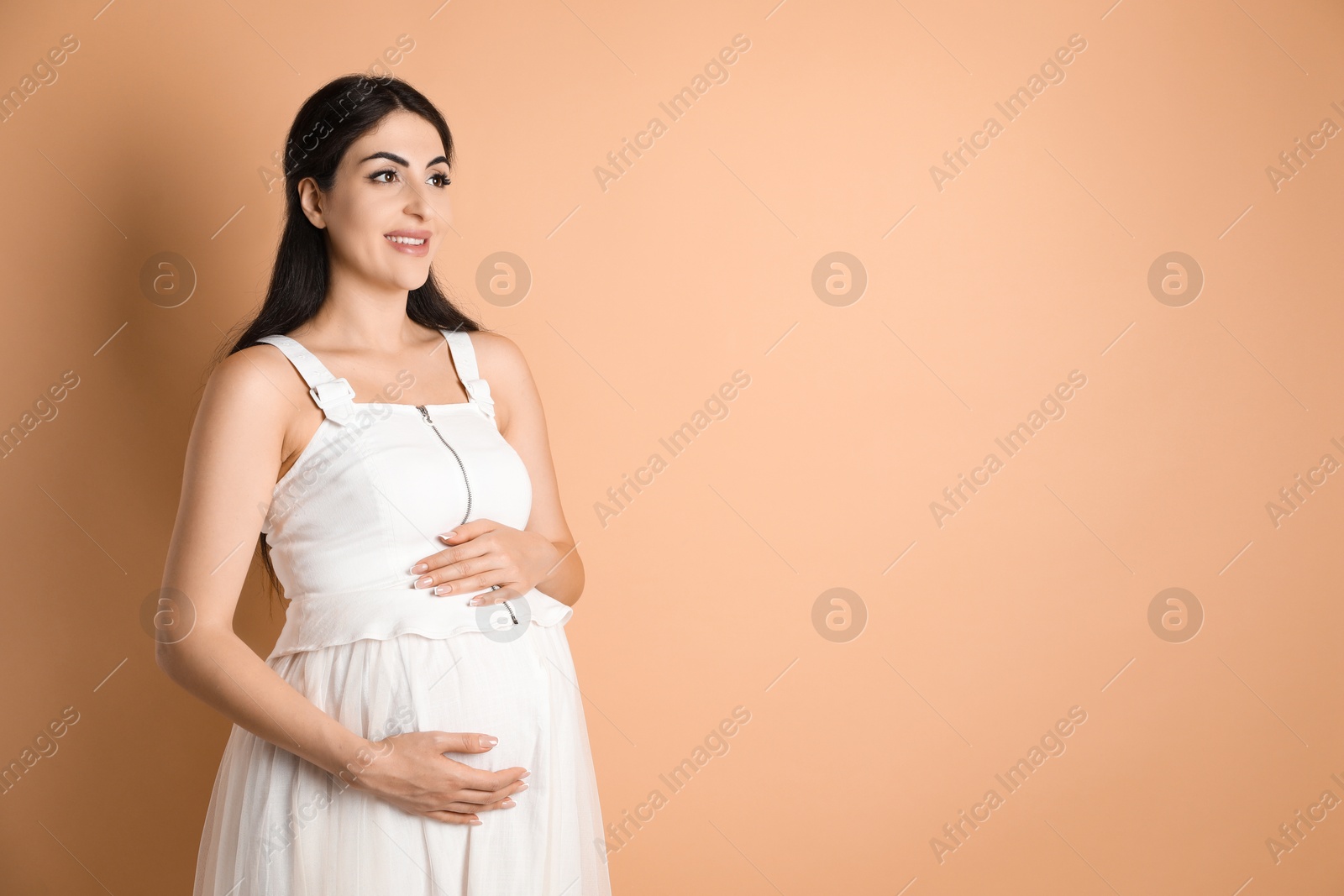 Photo of Portrait of beautiful pregnant woman on beige background, space for text