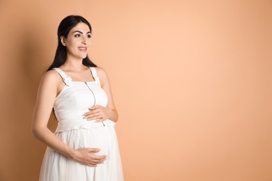 Photo of Portrait of beautiful pregnant woman on beige background, space for text