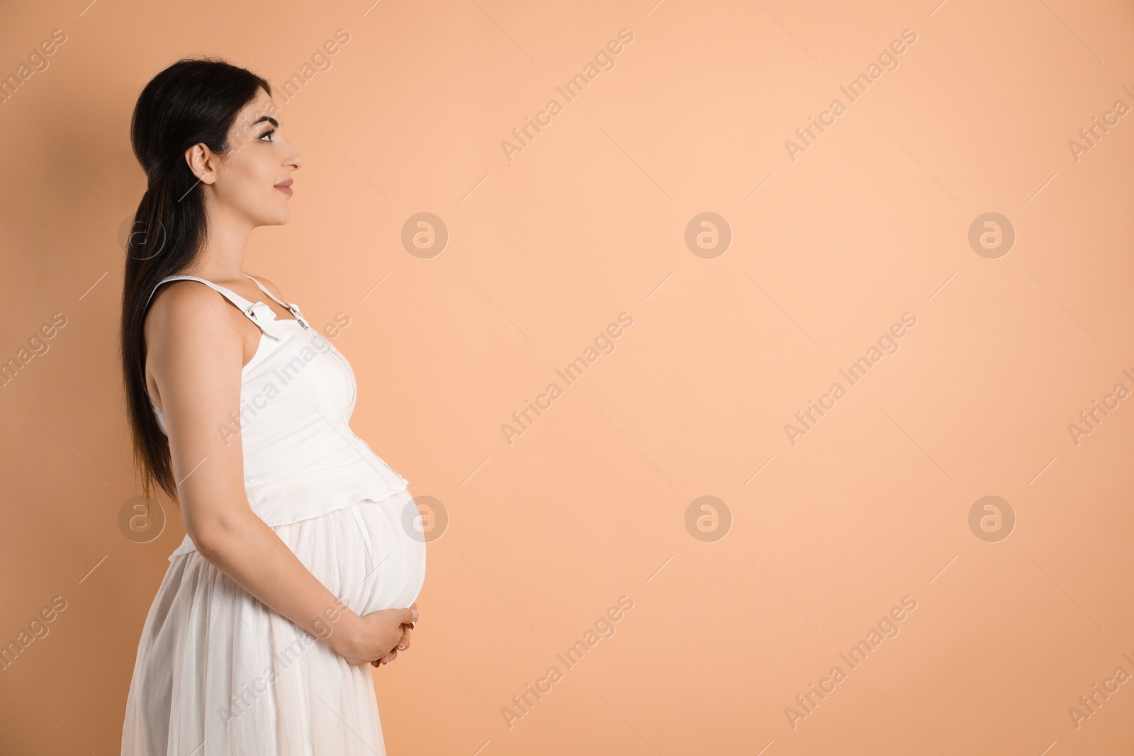 Photo of Portrait of beautiful pregnant woman on beige background, space for text