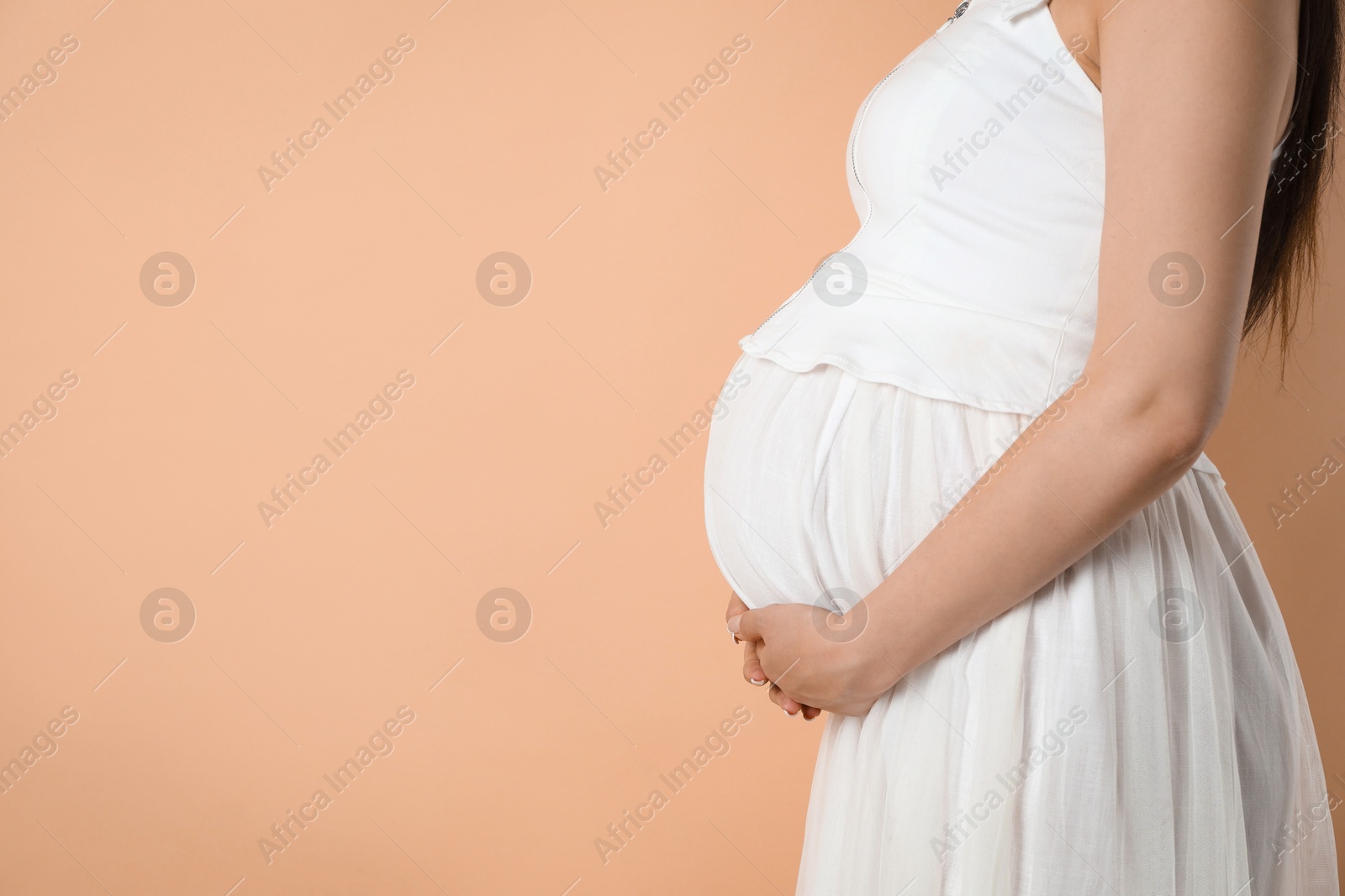 Photo of Young pregnant woman on beige background, closeup. Space for text