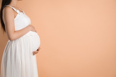 Photo of Young pregnant woman on beige background, closeup. Space for text