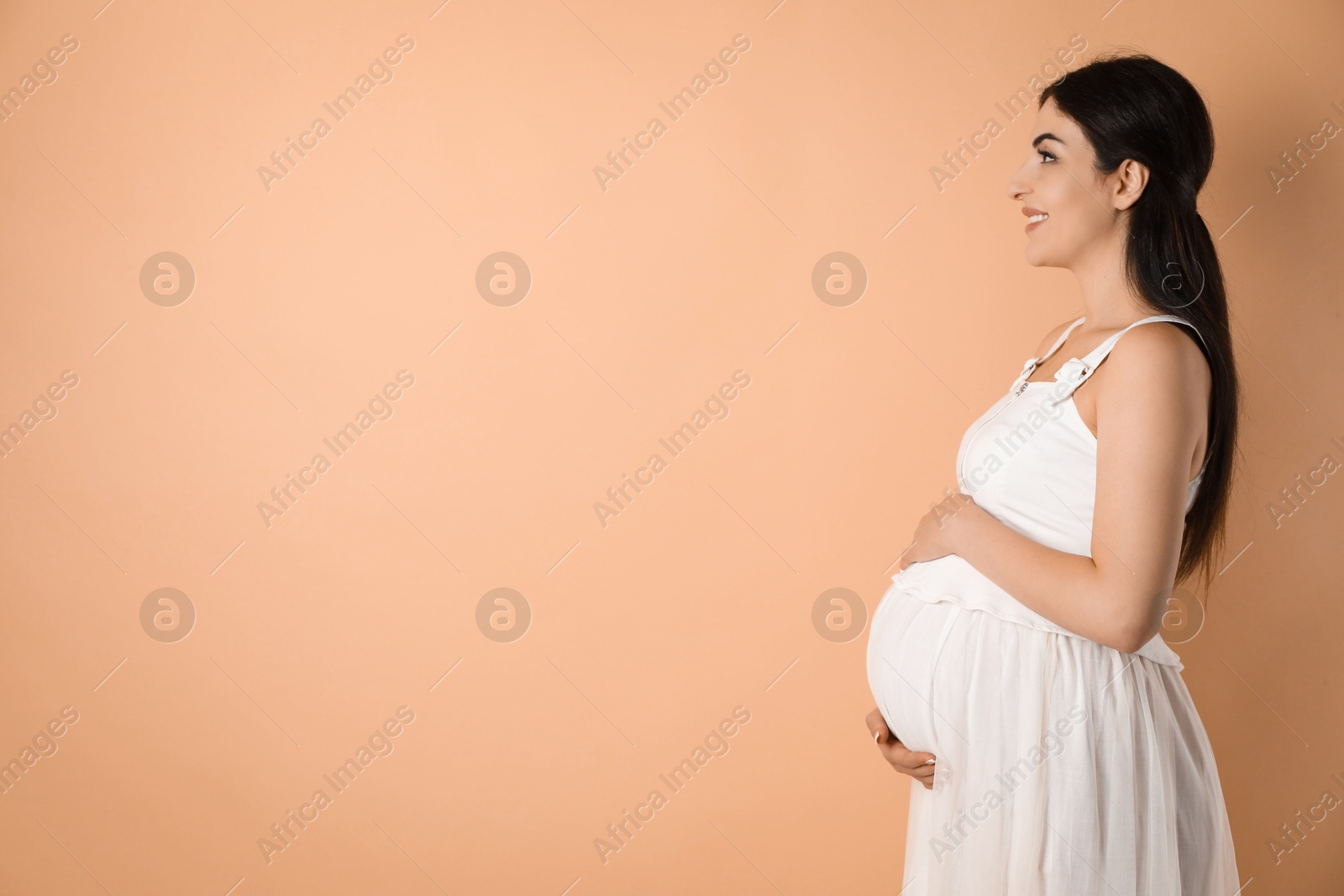 Photo of Portrait of beautiful pregnant woman on beige background, space for text