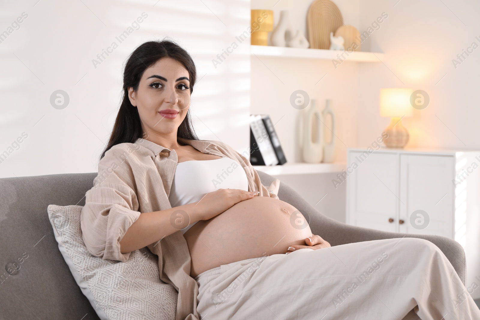 Photo of Young pregnant woman lying on bed at home