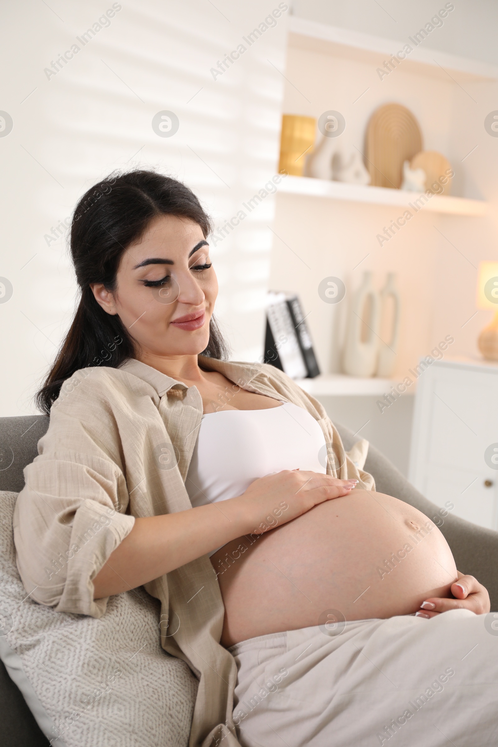 Photo of Young pregnant woman lying on bed at home