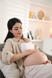 Photo of Young pregnant woman lying on bed at home