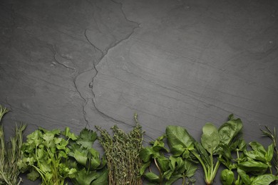 Photo of Different fresh herbs on grey textured table, flat lay. Space for text