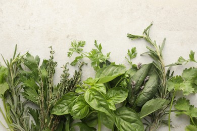 Photo of Different fresh herbs on light textured table, flat lay. Space for text