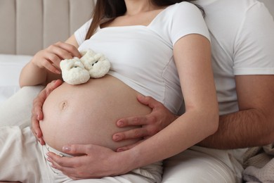 Photo of Pregnant woman with baby booties and her husband indoors, closeup