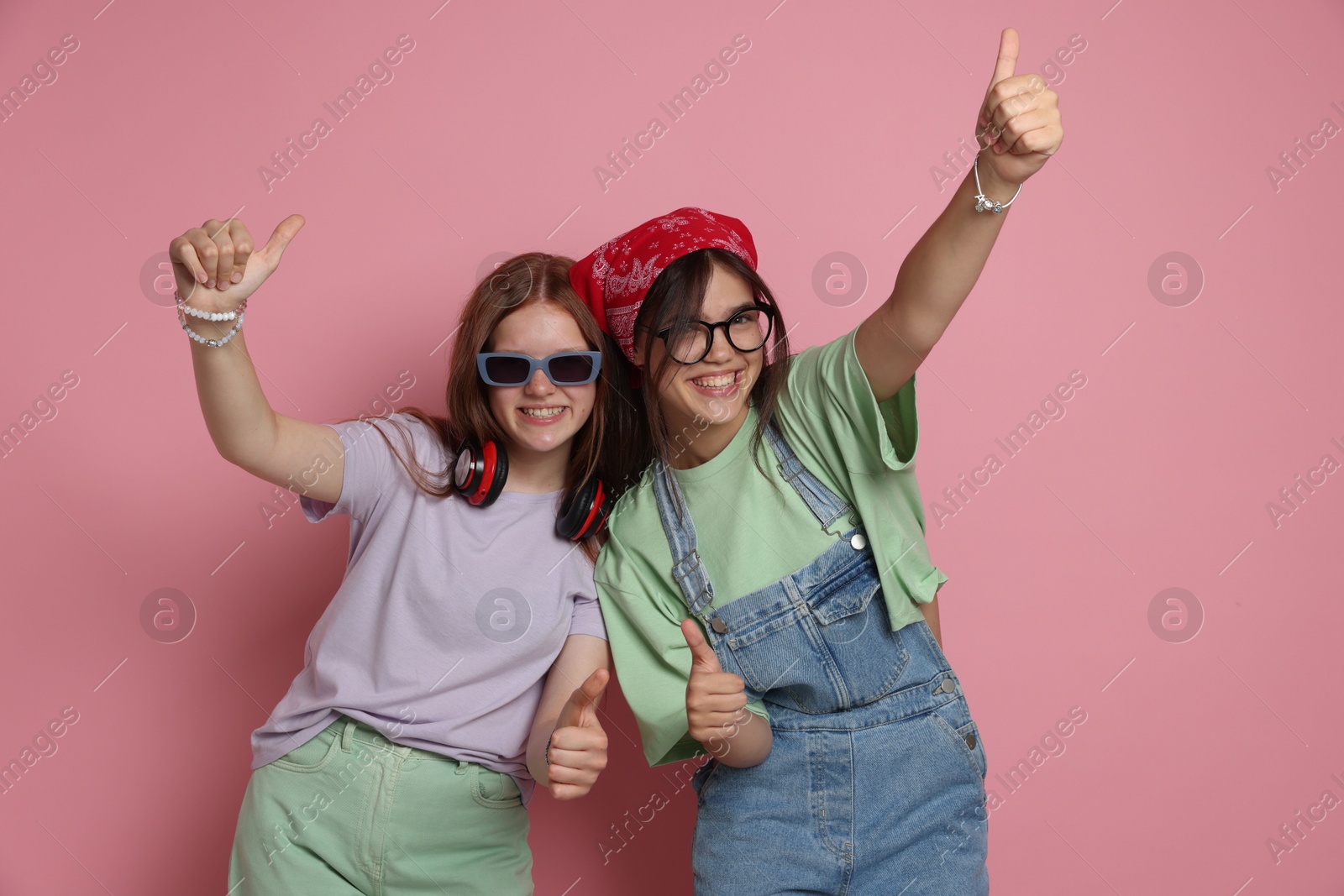 Photo of Happy teenage girls showing thumbs up on pink background