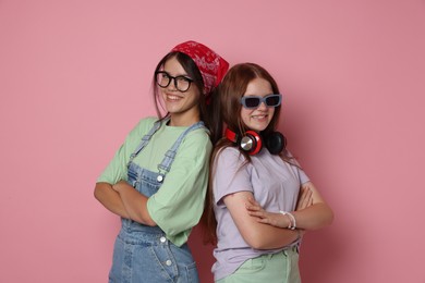 Happy teenage girls with crossed arms on pink background