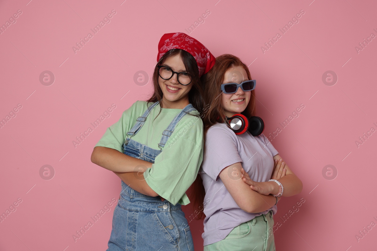 Photo of Happy teenage girls with crossed arms on pink background