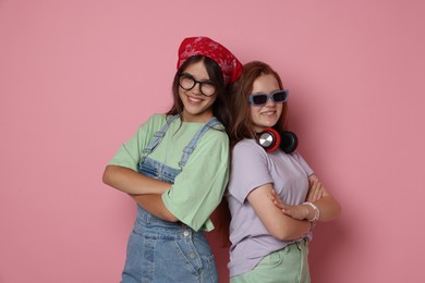 Happy teenage girls with crossed arms on pink background