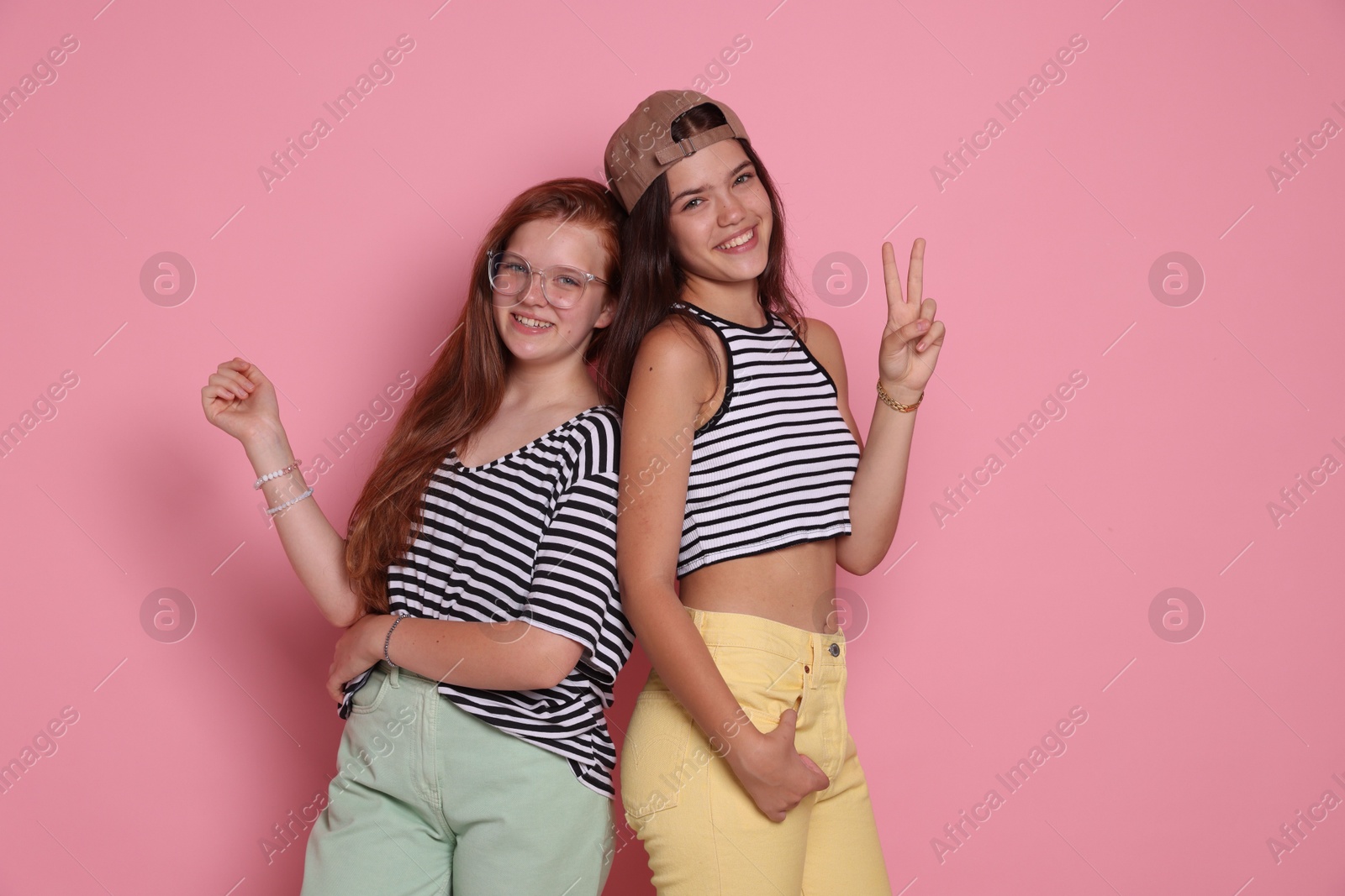 Photo of Happy teenage girls posing on pink background