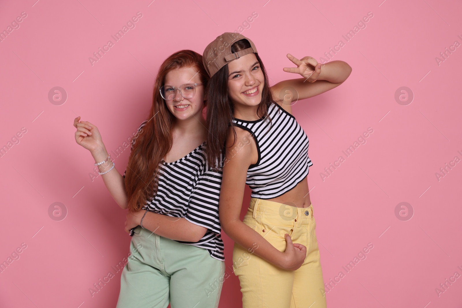 Photo of Happy teenage girls posing on pink background