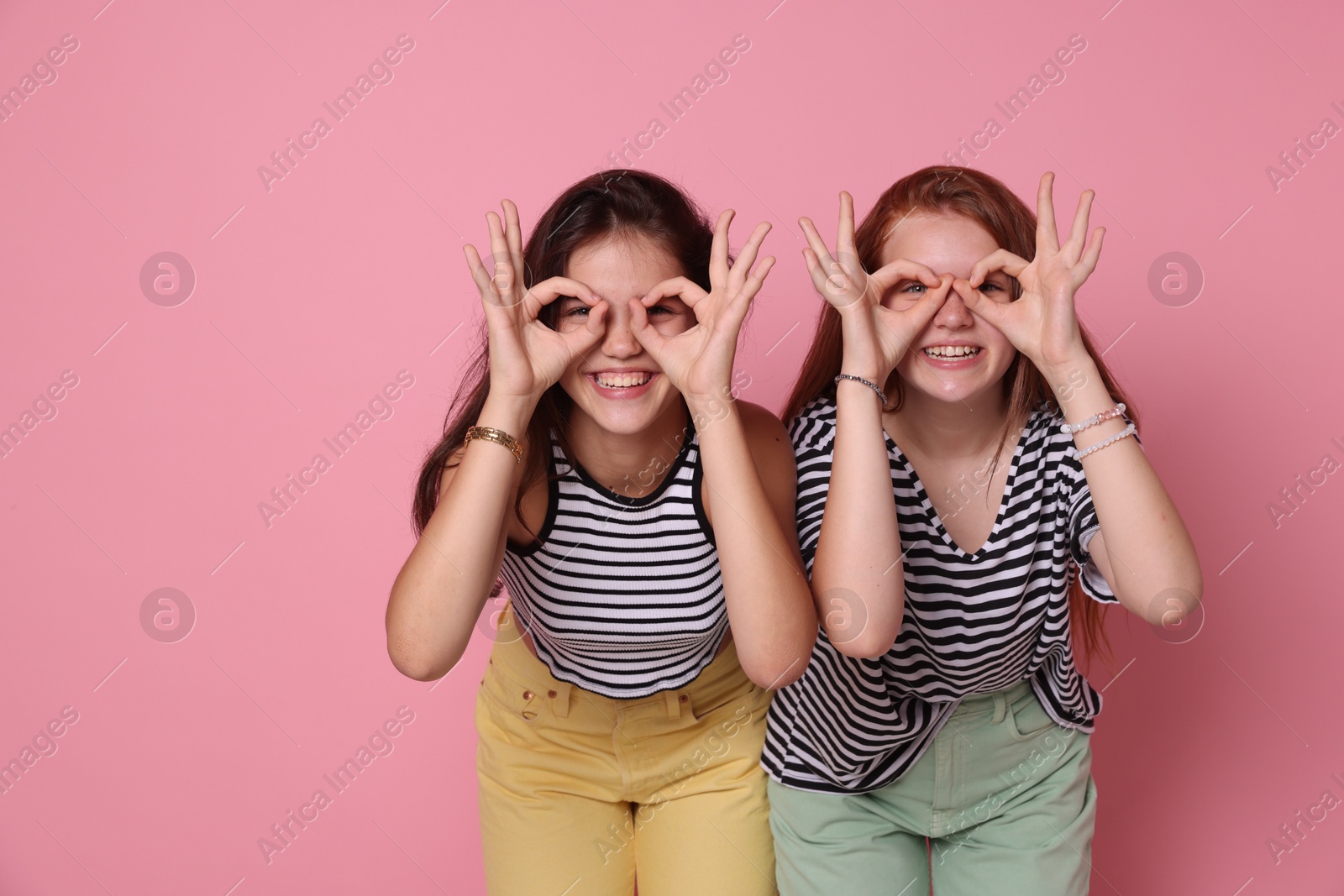 Photo of Happy teenage girls posing on pink background. Space for text