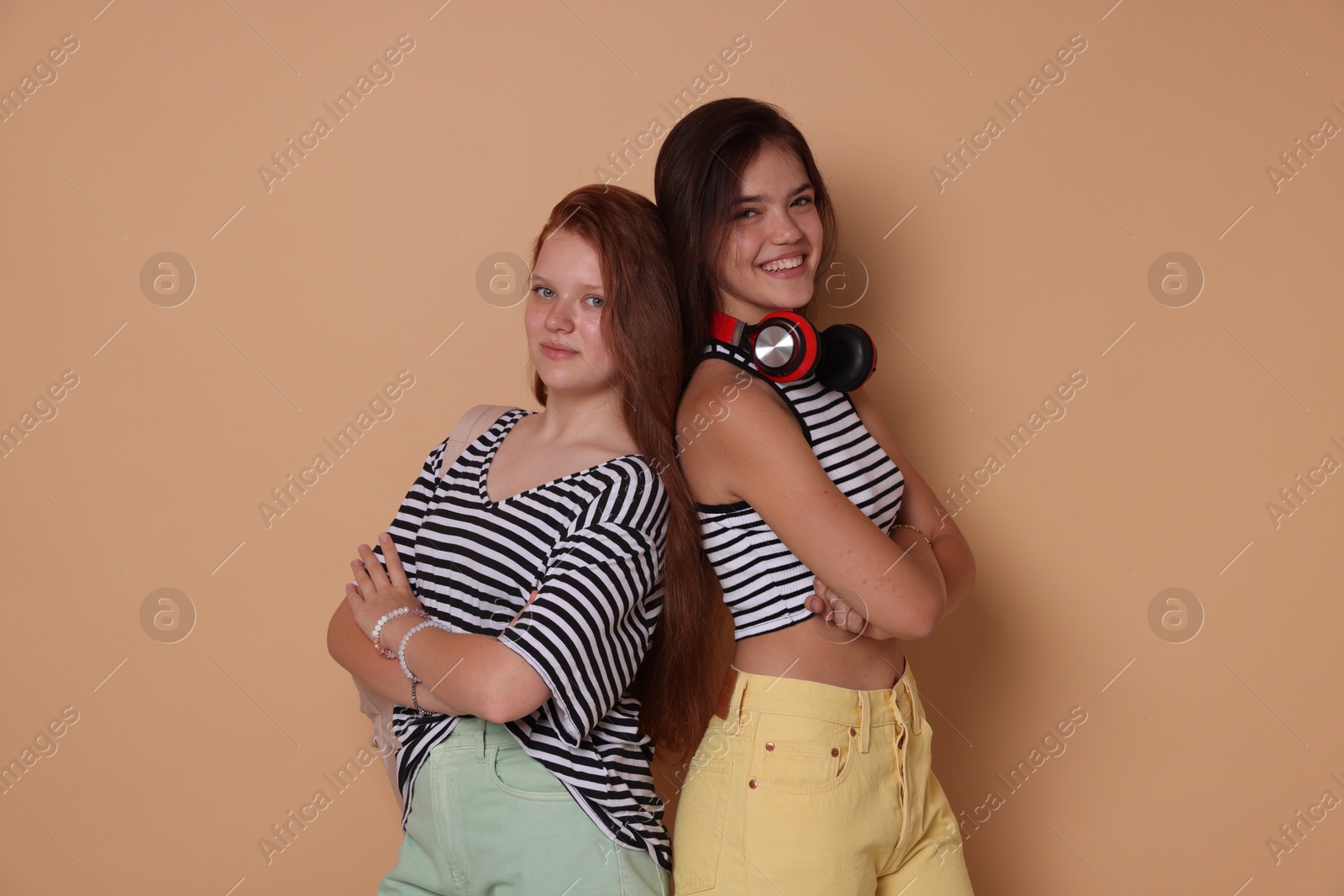 Photo of Happy teenage girls posing on beige background