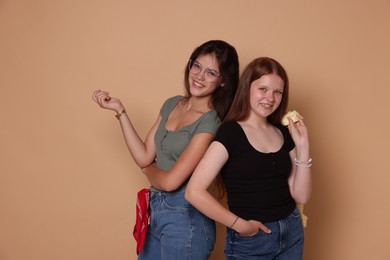 Photo of Happy teenage girls posing on beige background. Space for text