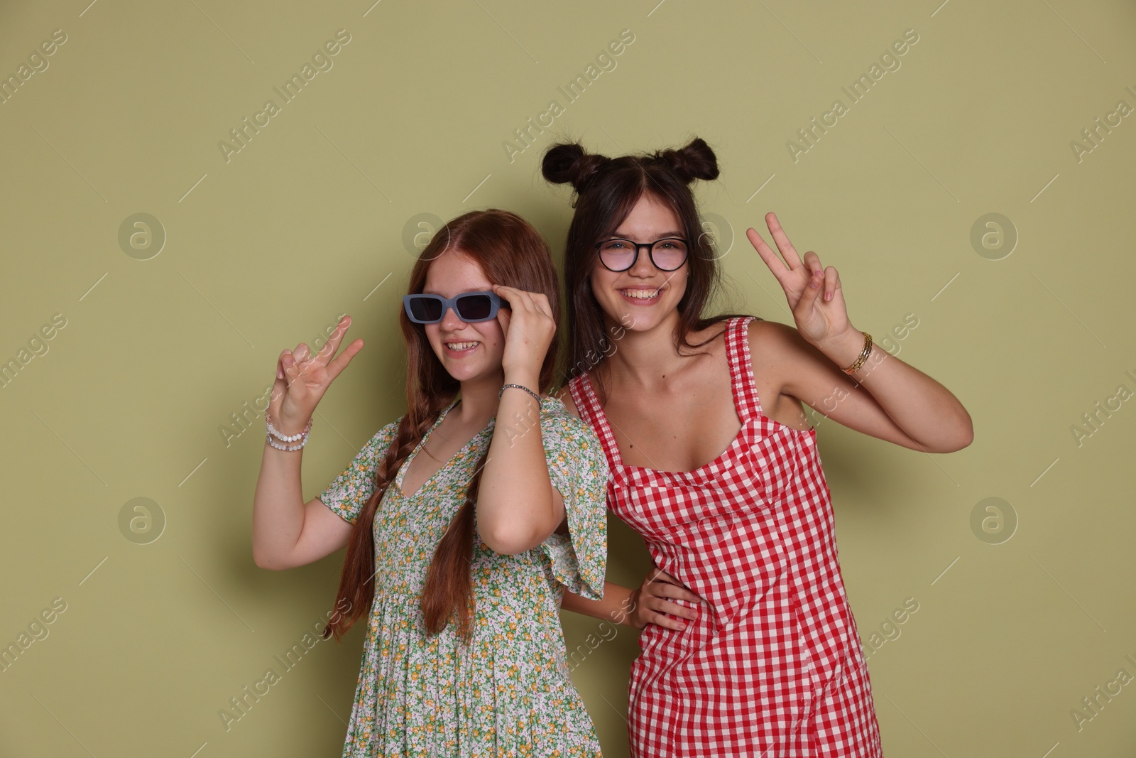 Photo of Happy teenage girls showing peace signs on green background