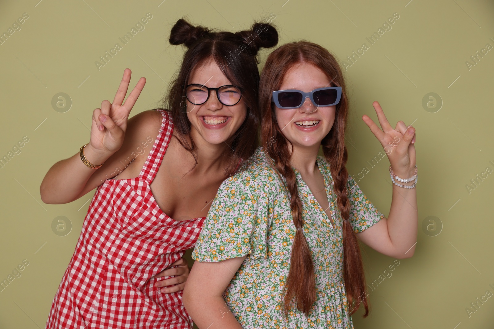 Photo of Happy teenage girls showing peace signs on green background