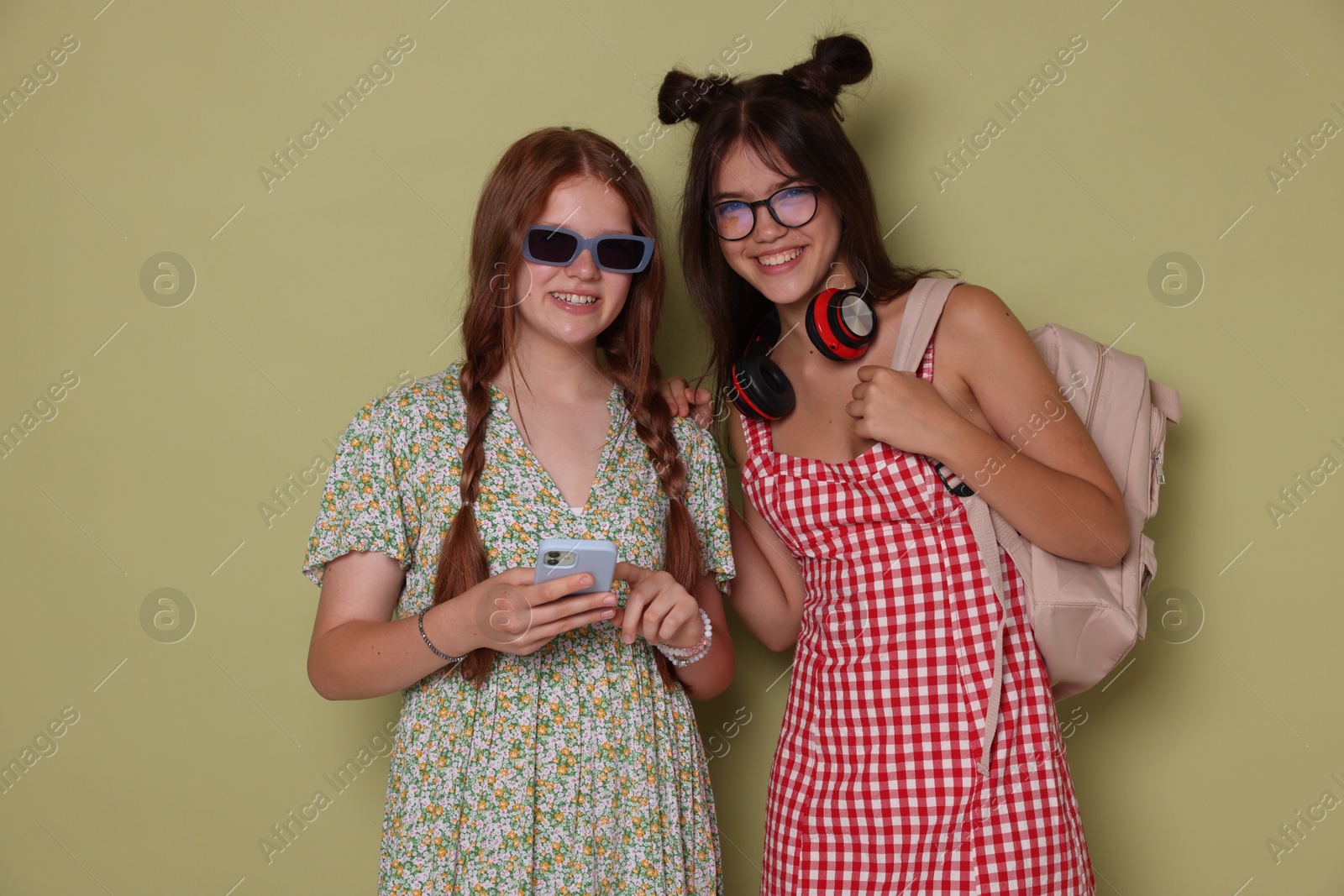 Photo of Happy teenage girls with smartphone on green background. Space for text