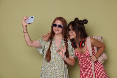 Photo of Happy teenage girls taking selfie on green background