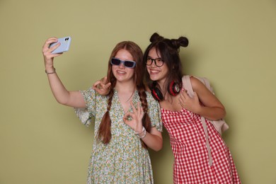 Photo of Happy teenage girls taking selfie on green background