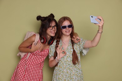 Photo of Happy teenage girls taking selfie on green background