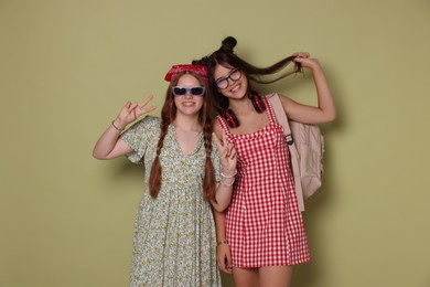 Happy teenage girls showing peace signs on green background