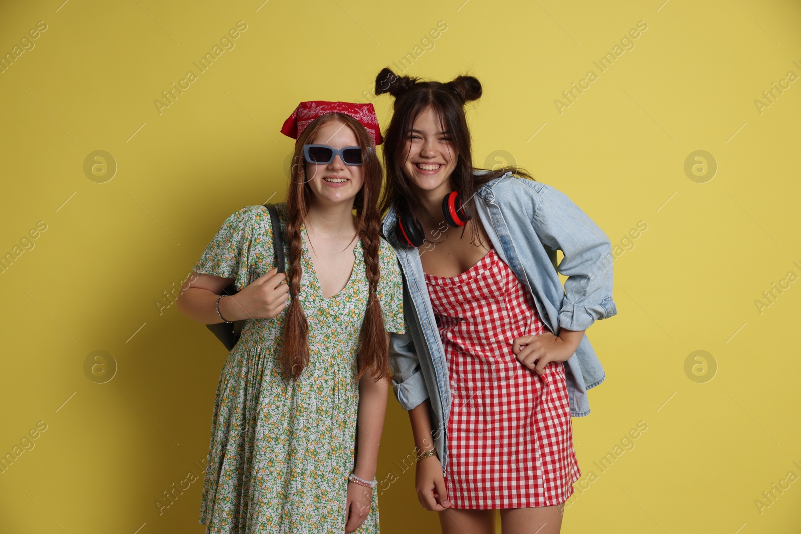 Photo of Happy teenage girls posing on yellow background