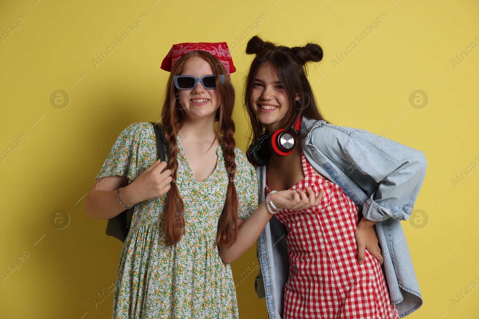 Photo of Happy teenage girls posing on yellow background