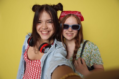 Photo of Happy teenage girls taking selfie on yellow background