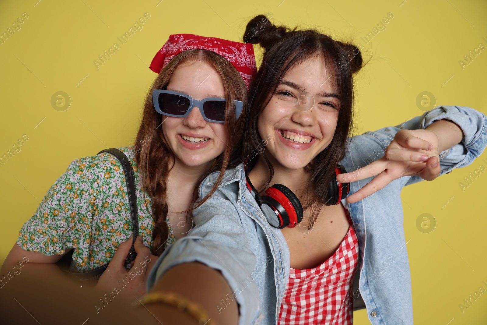 Photo of Happy teenage girls taking selfie on yellow background