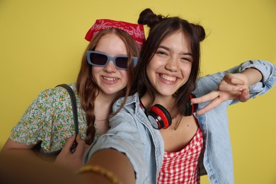 Happy teenage girls taking selfie on yellow background