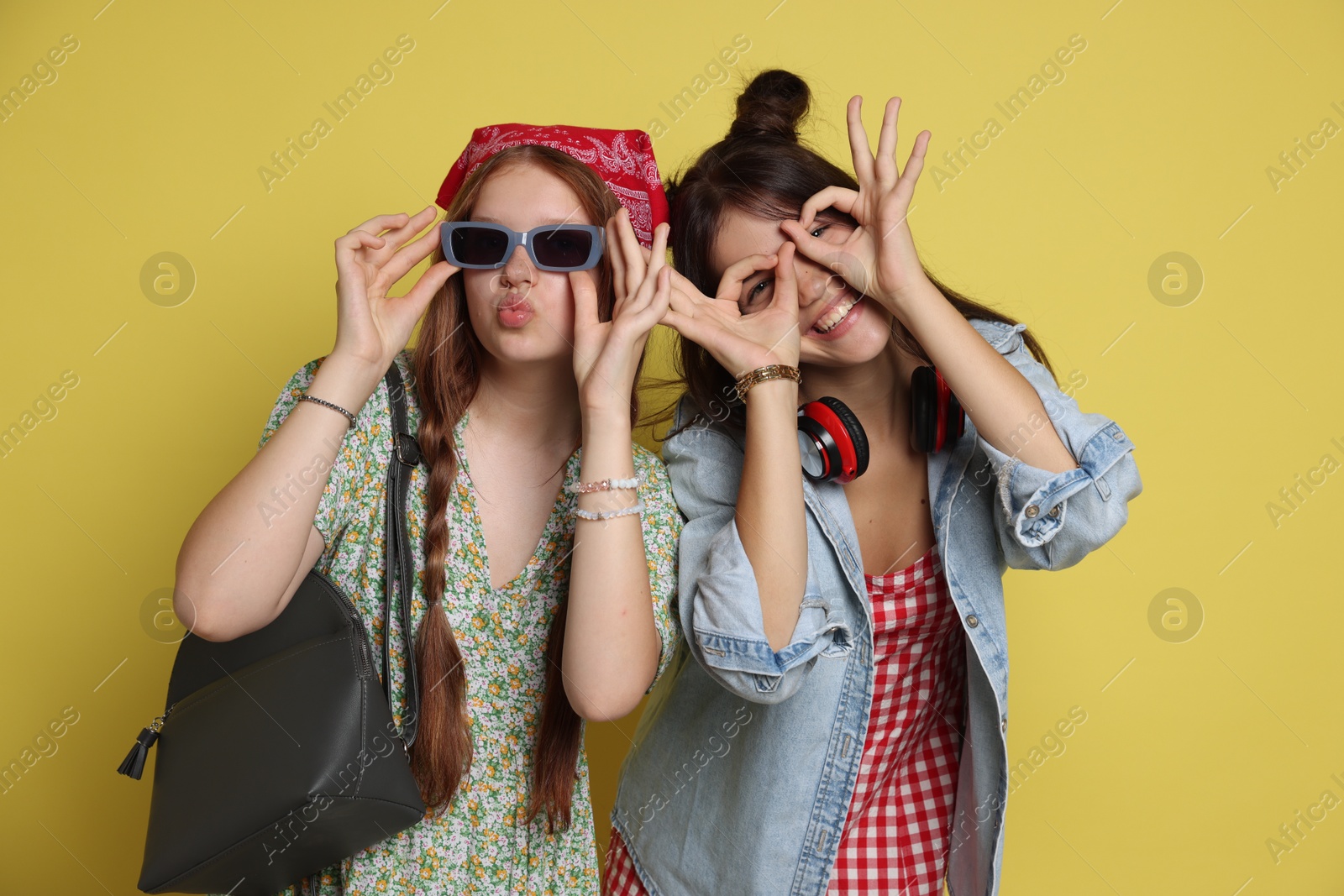 Photo of Funny teenage girls posing on yellow background