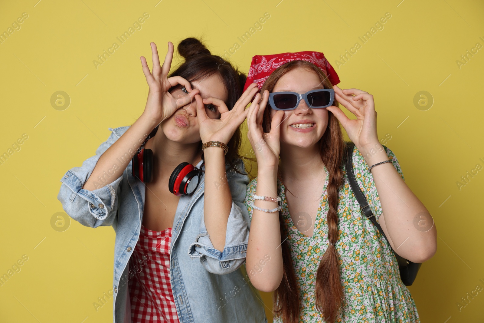 Photo of Funny teenage girls posing on yellow background