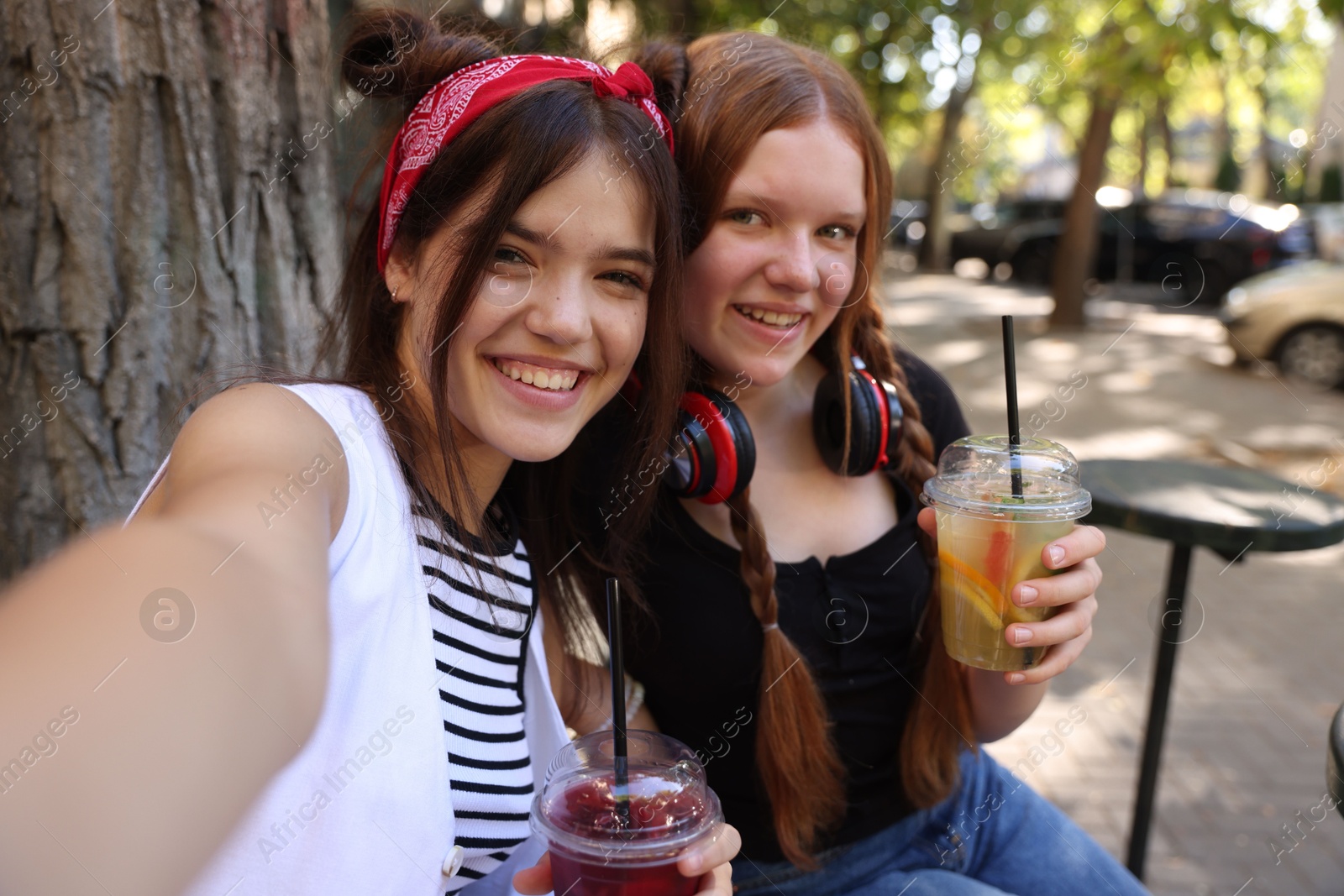 Photo of Happy teenage friends taking selfie in outdoor cafe