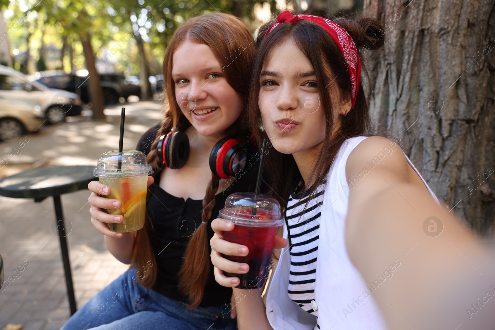 Photo of Happy teenage friends taking selfie in outdoor cafe