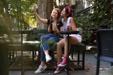 Photo of Happy teenage friends taking selfie in outdoor cafe