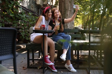 Happy teenage friends taking selfie in outdoor cafe