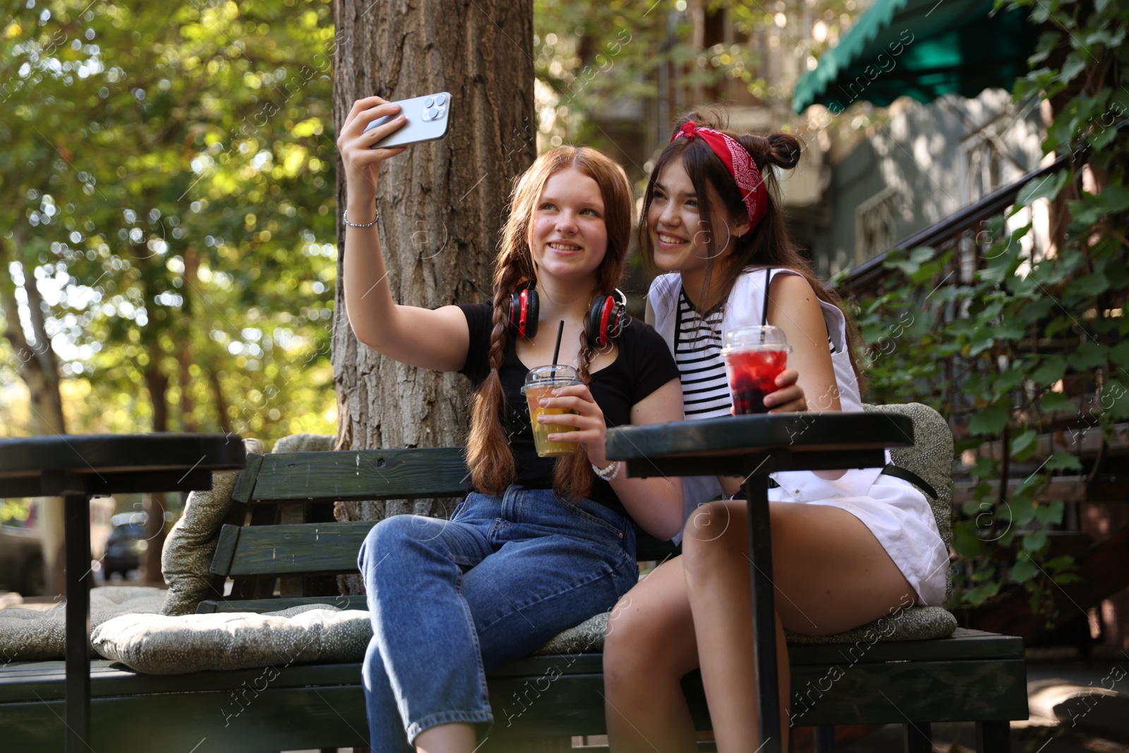 Photo of Happy teenage friends taking selfie in outdoor cafe